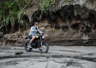 Man in cap riding motorcycle on beach. Moto cross dirtbiker on beach sunset on Bali. Young hipster