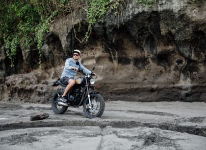 Man in cap riding motorcycle on beach. Moto cross dirtbiker on beach sunset on Bali. Young hipster