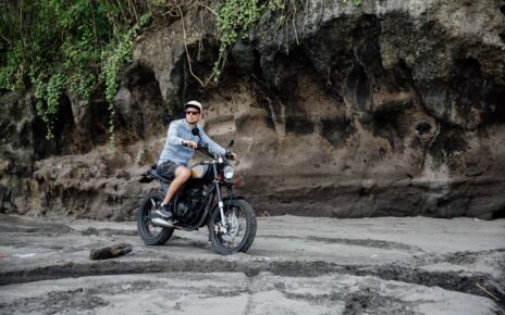 Man in cap riding motorcycle on beach. Moto cross dirtbiker on beach sunset on Bali. Young hipster