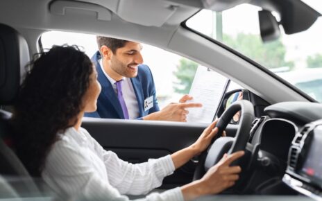 Young woman sitting inside car, having conversation with sales manager