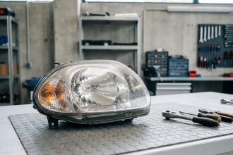 Phare avant d'origine Renault Clio 2 posé sur un établi d'atelier automobile avec outils
